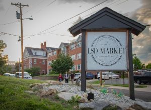 The Lee Street Deli Market sign in Columbia, Mo., stands under the partially cloudy sky as residents walk to the venue for the Music Factory Semester Sendoff on April 30. Despite delays due to the rain, live performances began at 7 p.m. and continued into the evening. 